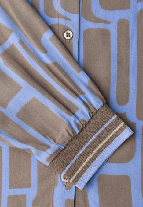 Nahaufnahme eines Hemdsärmlings mit Reißverschluss, taupe und hellblaues geometrisches Muster.